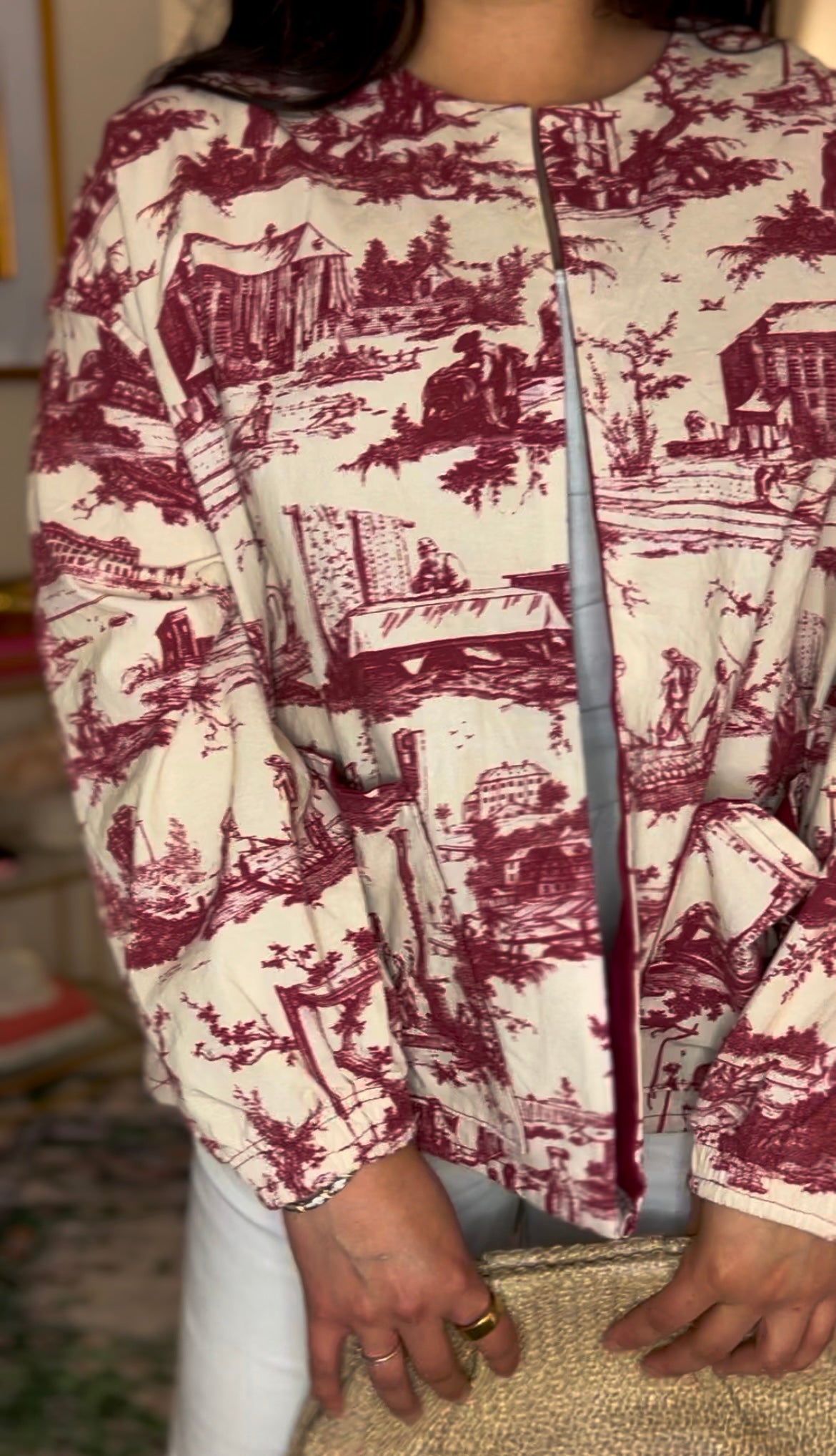 Handmade French toile jacket in vintage maroon and cream, featuring countryside rodeo scenes, raw edges, and a structured silhouette. Cut from rare deadstock upholstery fabric.