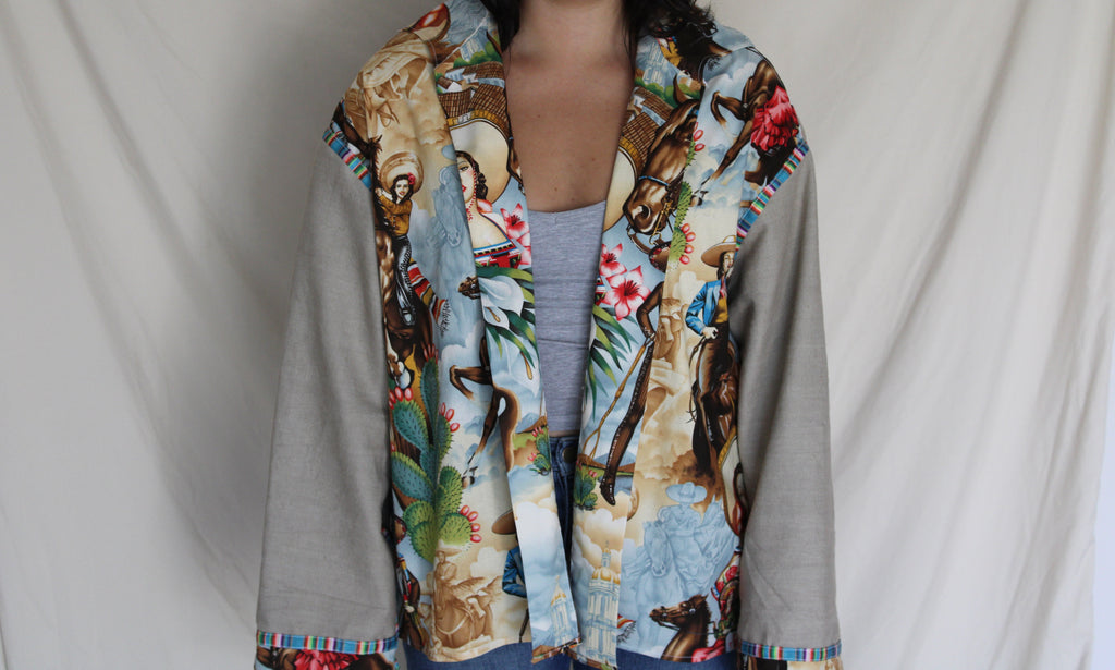 colorful western-inspired oversized jacket featuring a bold cowboy desert print on the front and serape stripe trim on the cuffs. Handmade using upcycled fabric with neural tan sleeves and sustainable construction. 