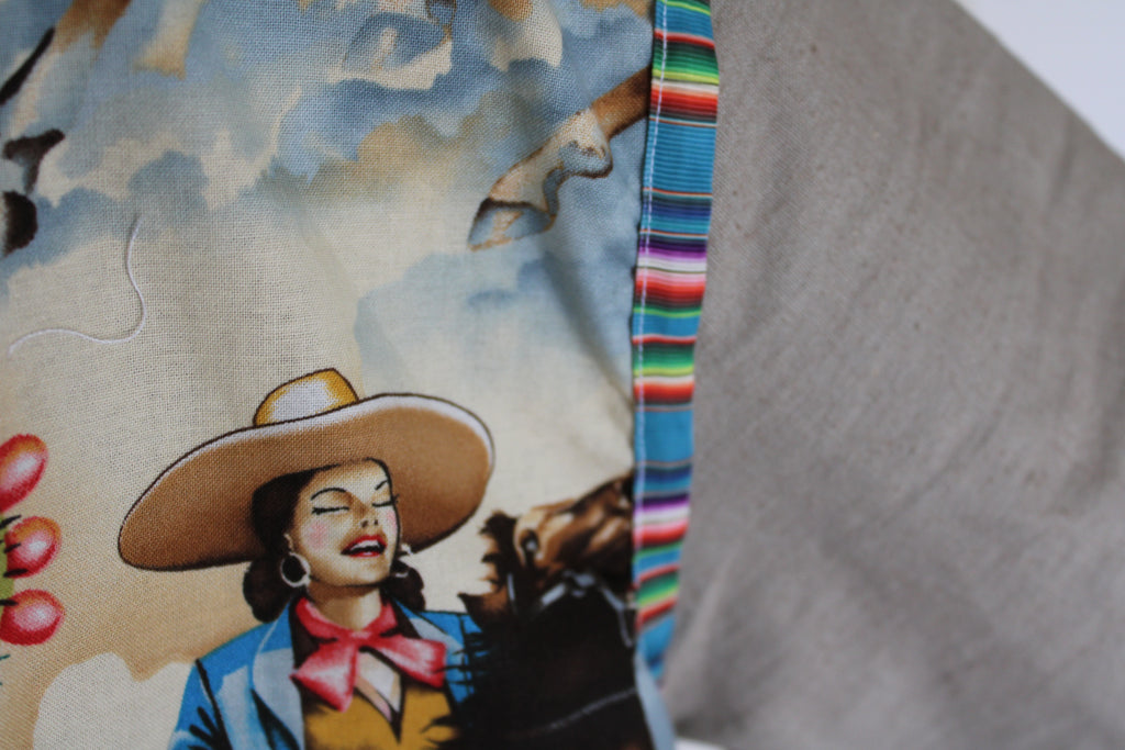 colorful western-inspired oversized jacket featuring a bold cowboy desert print on the front and serape stripe trim on the cuffs. Handmade using upcycled fabric with neural tan sleeves and sustainable construction. 