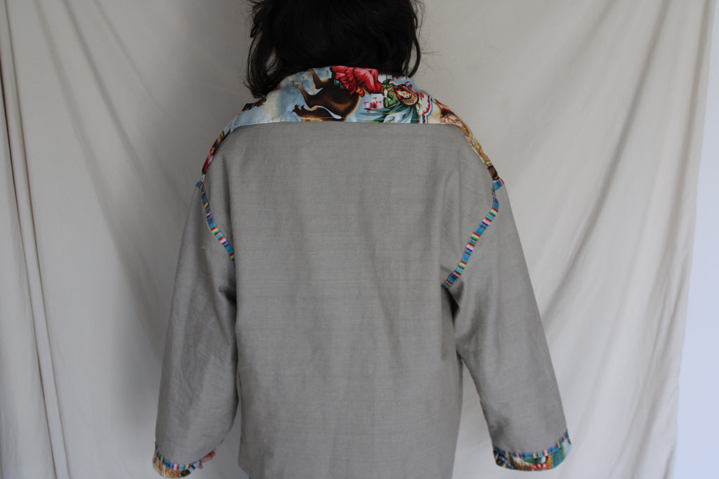 colorful western-inspired oversized jacket featuring a bold cowboy desert print on the front and serape stripe trim on the cuffs. Handmade using upcycled fabric with neural tan sleeves and sustainable construction. 
