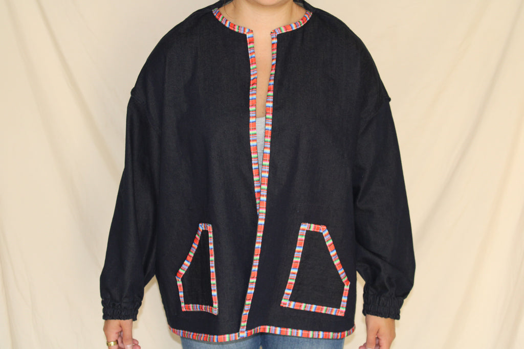 Handmade black denim jacket featuring a large western cowgirl collage patch on the back with vintage rodeo artwork and desert motifs. Accented with colorful serape trim along the hem and crafted from upcycled materials for a bold, sustainable statement. 