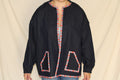 Handmade black denim jacket featuring a large western cowgirl collage patch on the back with vintage rodeo artwork and desert motifs. Accented with colorful serape trim along the hem and crafted from upcycled materials for a bold, sustainable statement. 