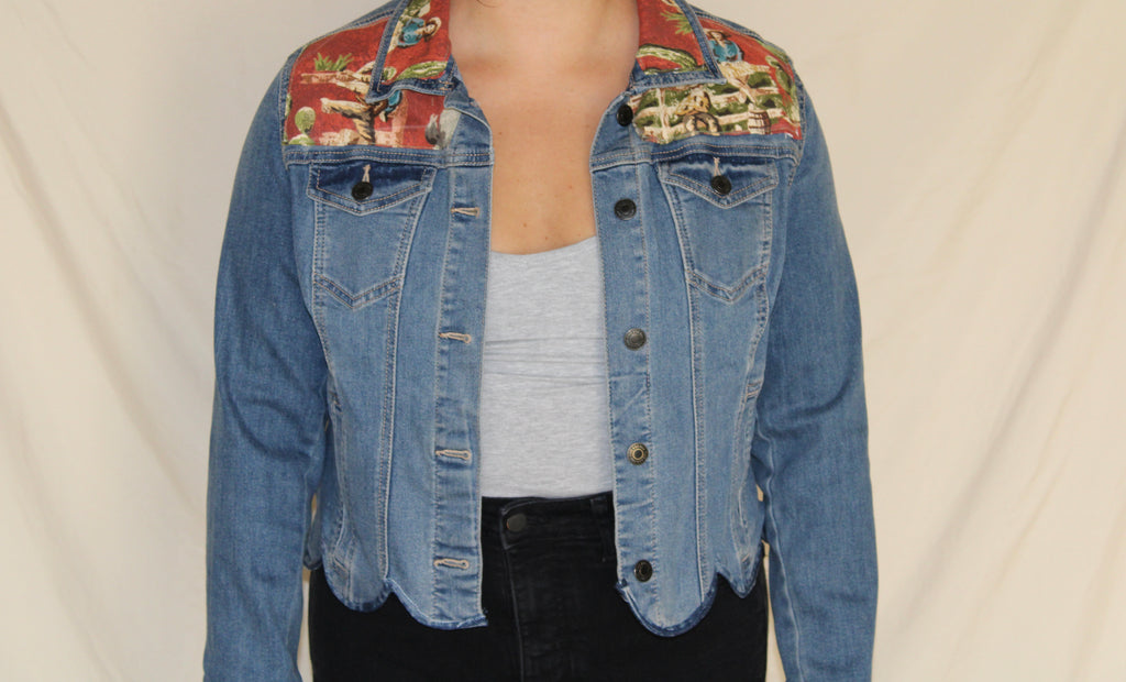 Upcycled denim jacket with scalloped hem and a bold red vintage cowboy panel on the back. Features a lassoing rodeo rider and cactus print, finished with a western-inspired collar and contrast stitching. Handmade for a one-of-a-kind, sustainable statement piece. 