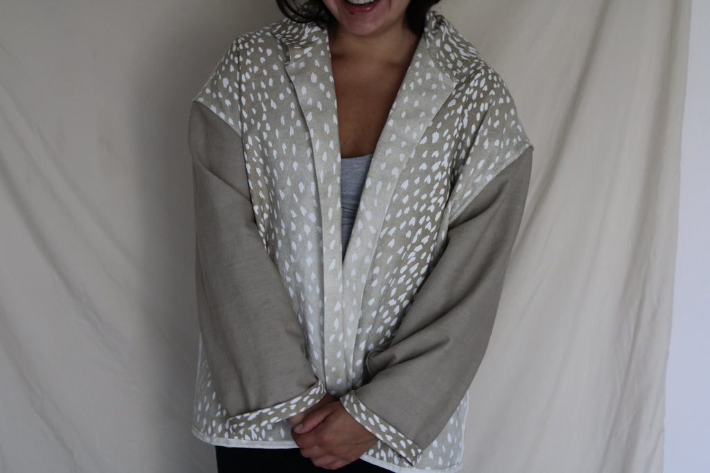 Handmade jacket with tan sleeves and an oversized back panel featuring a white antelope inspired print. Ethically crafted from rescued textiles, this one of a kind piece blends cozy comfort with a bold southern and western flair. 