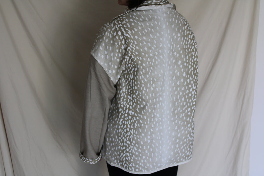 Handmade jacket with tan sleeves and an oversized back panel featuring a white antelope inspired print. Ethically crafted from rescued textiles, this one of a kind piece blends cozy comfort with a bold southern and western flair. 