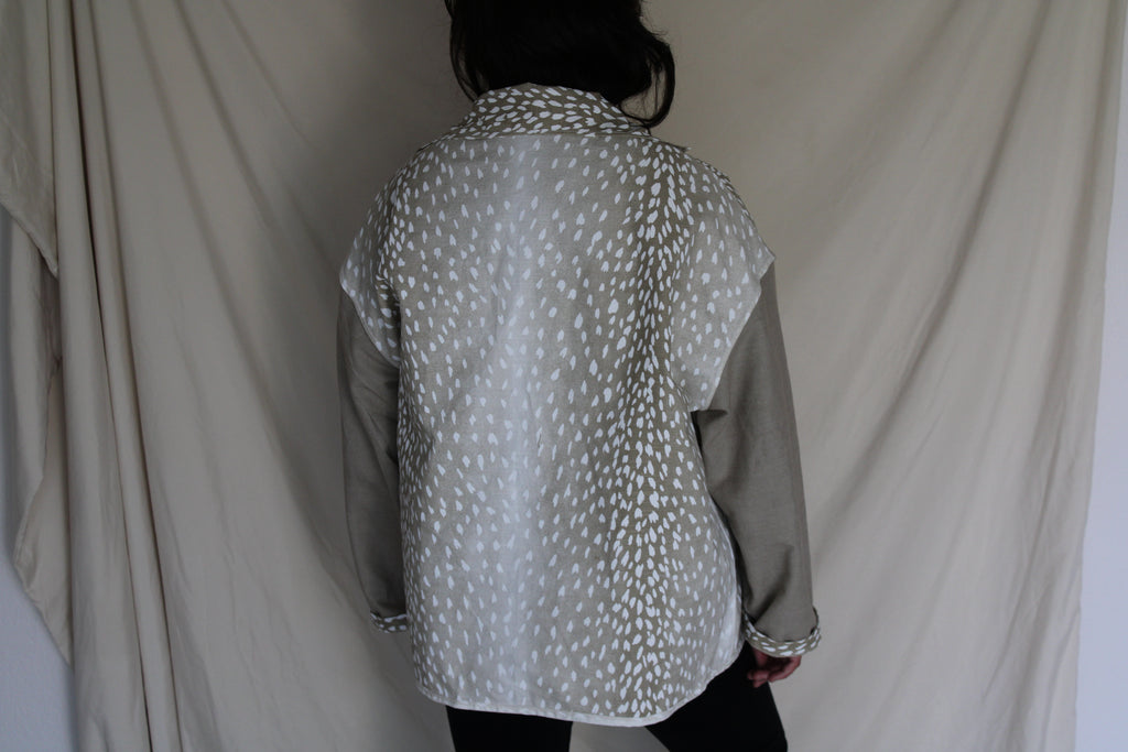 Handmade jacket with tan sleeves and an oversized back panel featuring a white antelope inspired print. Ethically crafted from rescued textiles, this one of a kind piece blends cozy comfort with a bold southern and western flair. 