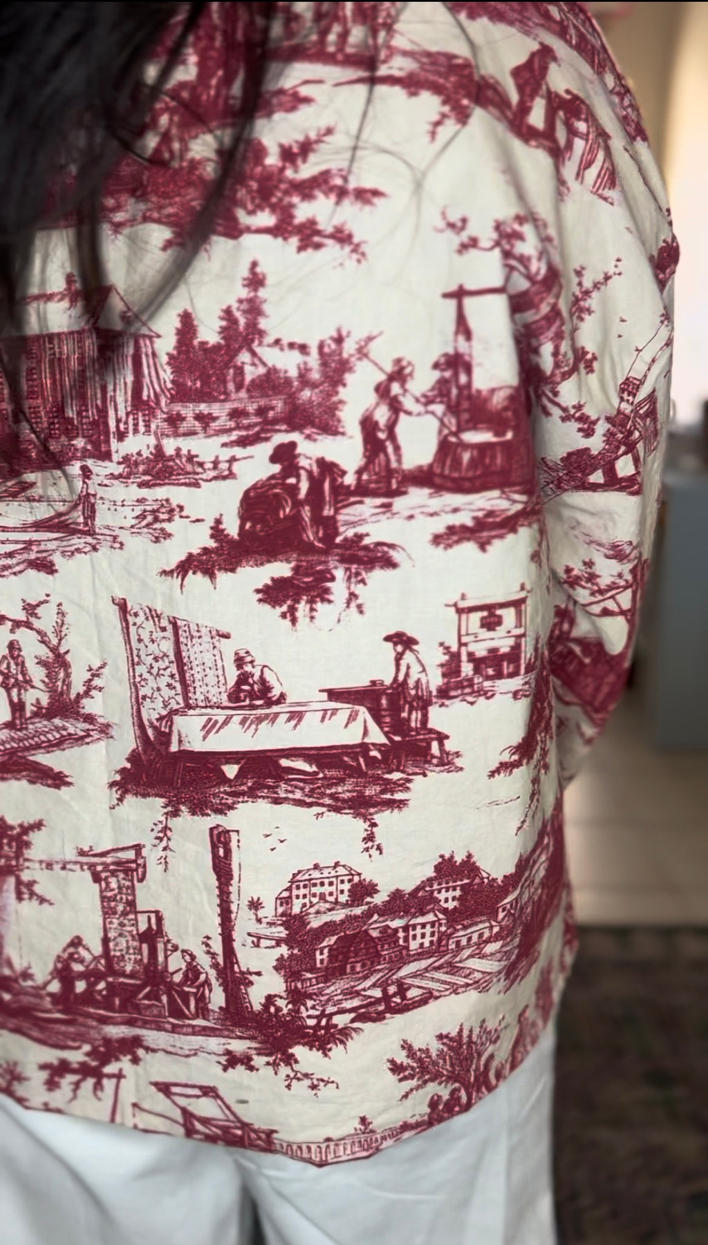 Handmade French toile jacket in vintage maroon and cream, featuring countryside rodeo scenes, raw edges, and a structured silhouette. Cut from rare deadstock upholstery fabric. 